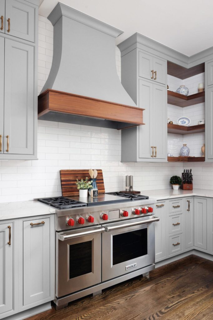 Custom kitchen range hood design with wood accents and gold hardware in an Alpharetta home remodel by JL Signature Designs.