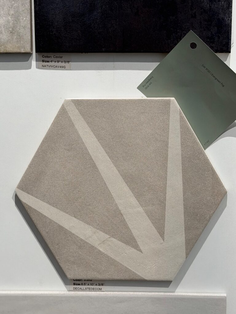 A large hexagonal floor tile with a geometric cream-colored starburst pattern on a light gray background, paired with a green Sherwin Williams "Evergreen Fog" paint swatch.