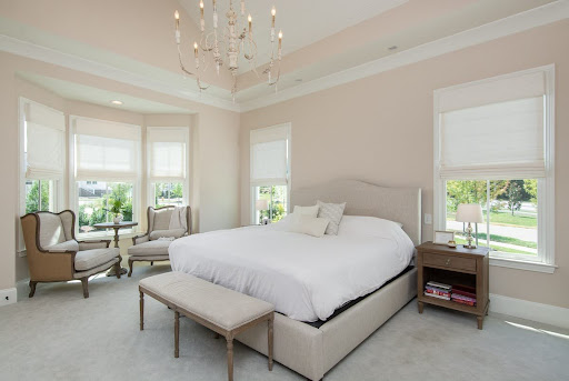 A serene, cozy bedroom featuring a neatly made bed with layered neutral linens, soft ambient bedside lighting, and natural wood accents creating a calming atmosphere.