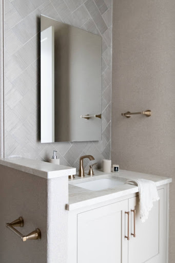 A modern bathroom vanity with a marble countertop, clean undermount sink, sleek gold fixtures, a large framed mirror, and organized luxury skincare products.