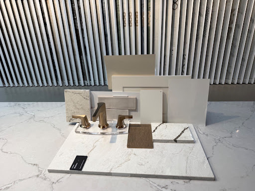 Interior design selection board displaying brushed brass plumbing fixtures, marble slabs, tile swatches, and cabinet finishes.