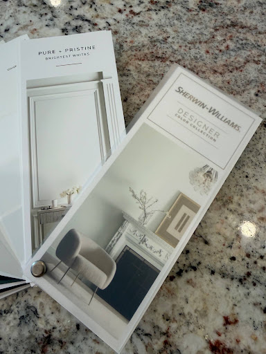 Sherwin-Williams paint fan decks displayed on a speckled granite countertop next to white trim samples.